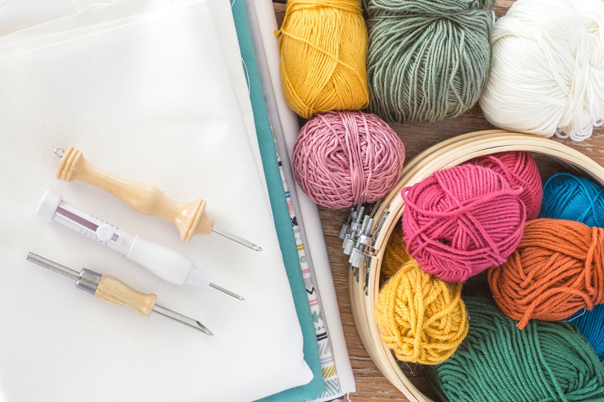 Materiales de punch needle con lanas de colores, aguja mágica y telas