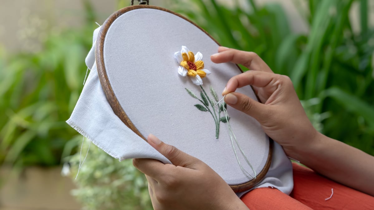 Mujer bordando flor sobre tela como actividad relajante