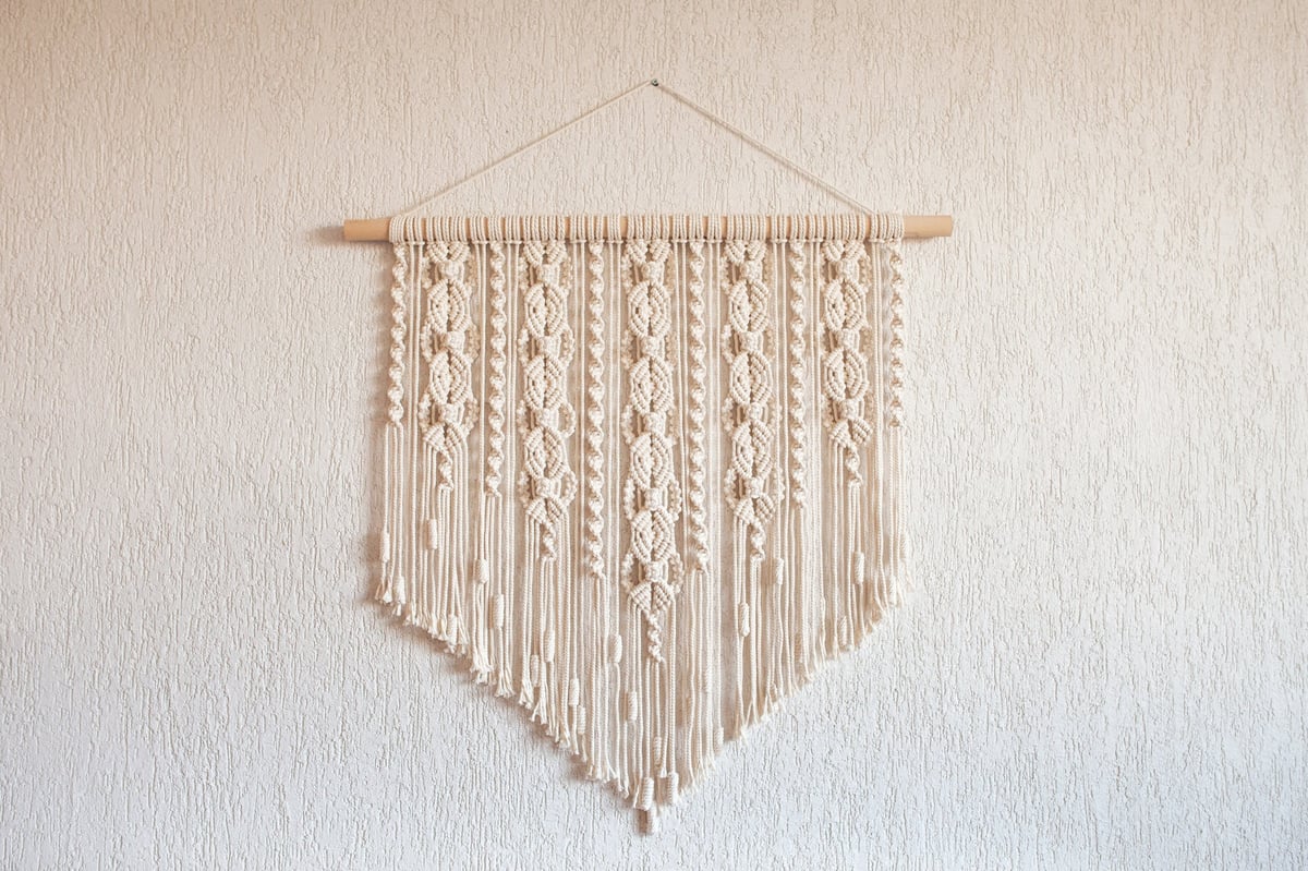 Decoración de pared en macramé artesanal colgada en pared blanca