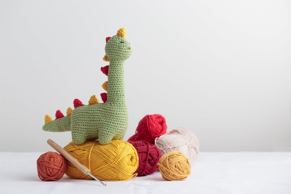 Dinosaurio verde tejido a crochet con ovillo de lana