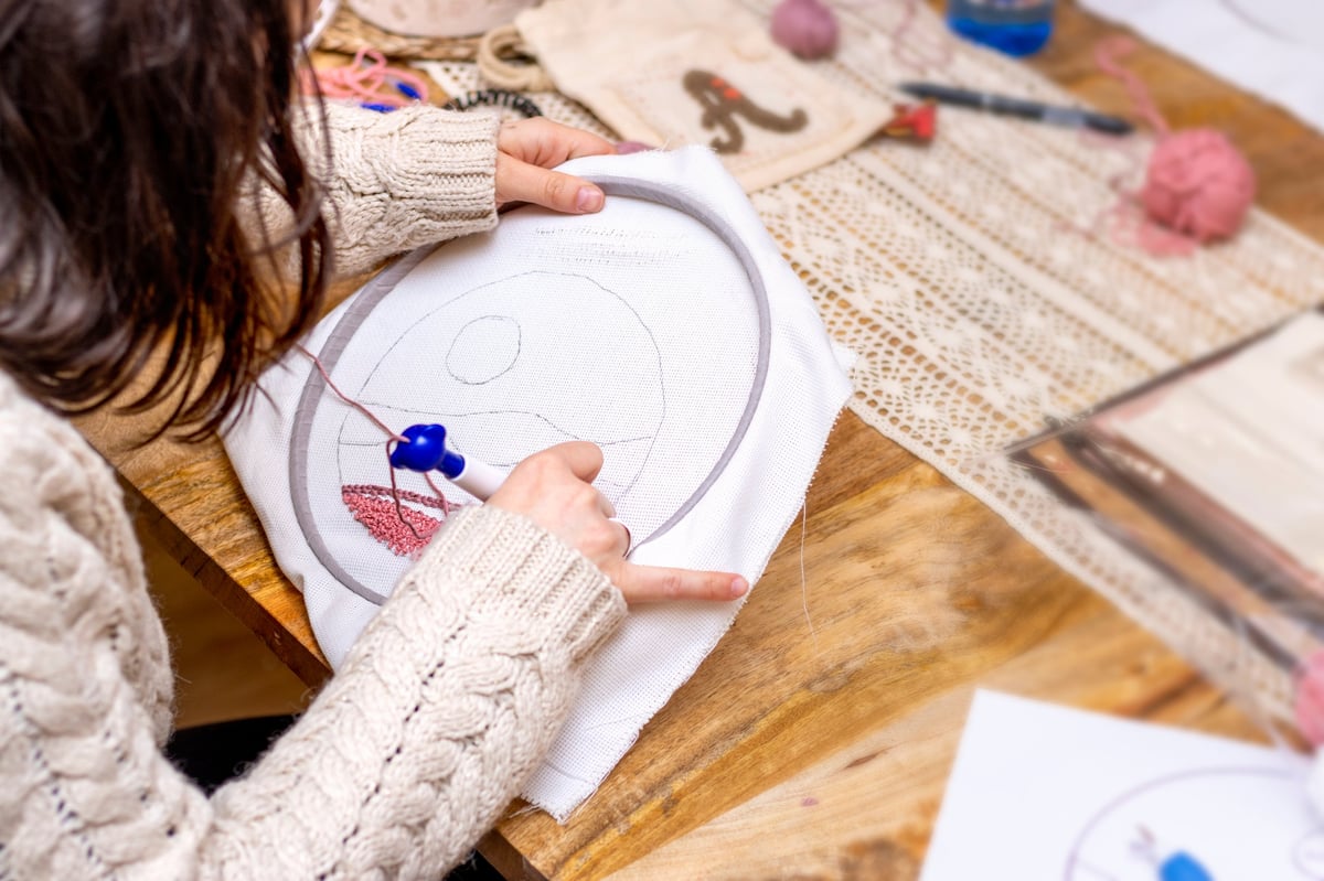 Taller de punch needle — manos dibujando boceto sobre tela para bordar