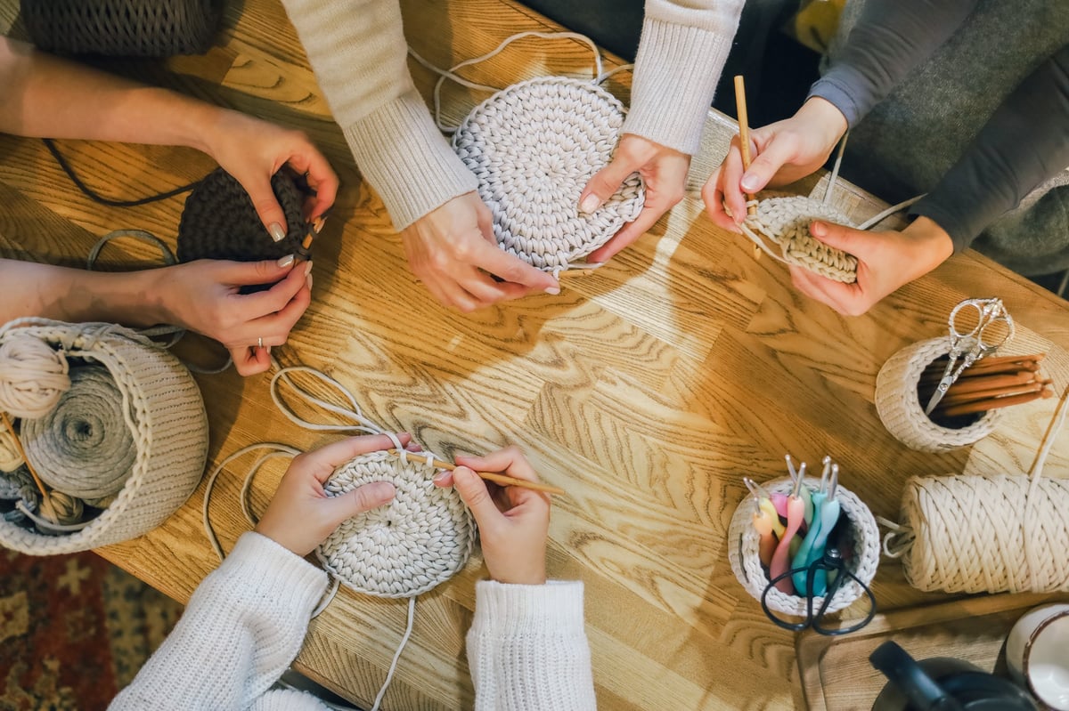 Mujeres tejiendo crochet juntas en taller creativo con lanas y agujas