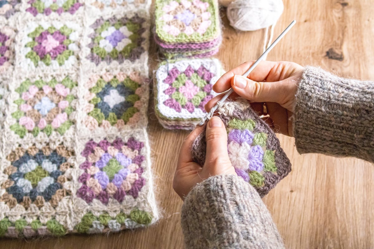 Manos uniendo granny squares en proyecto de crochet en progreso