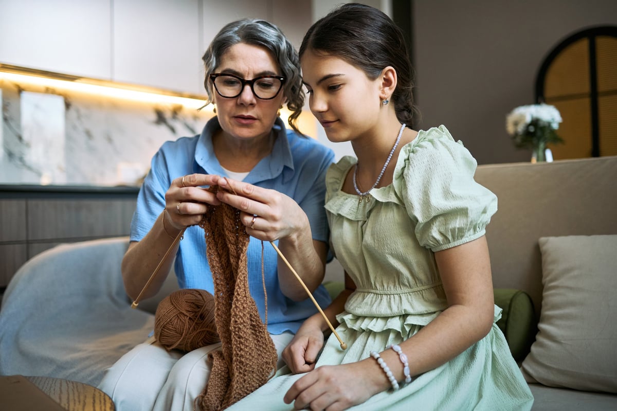 Mujer enseñando a tejer crochet a joven en casa — aprendizaje y tradición textil