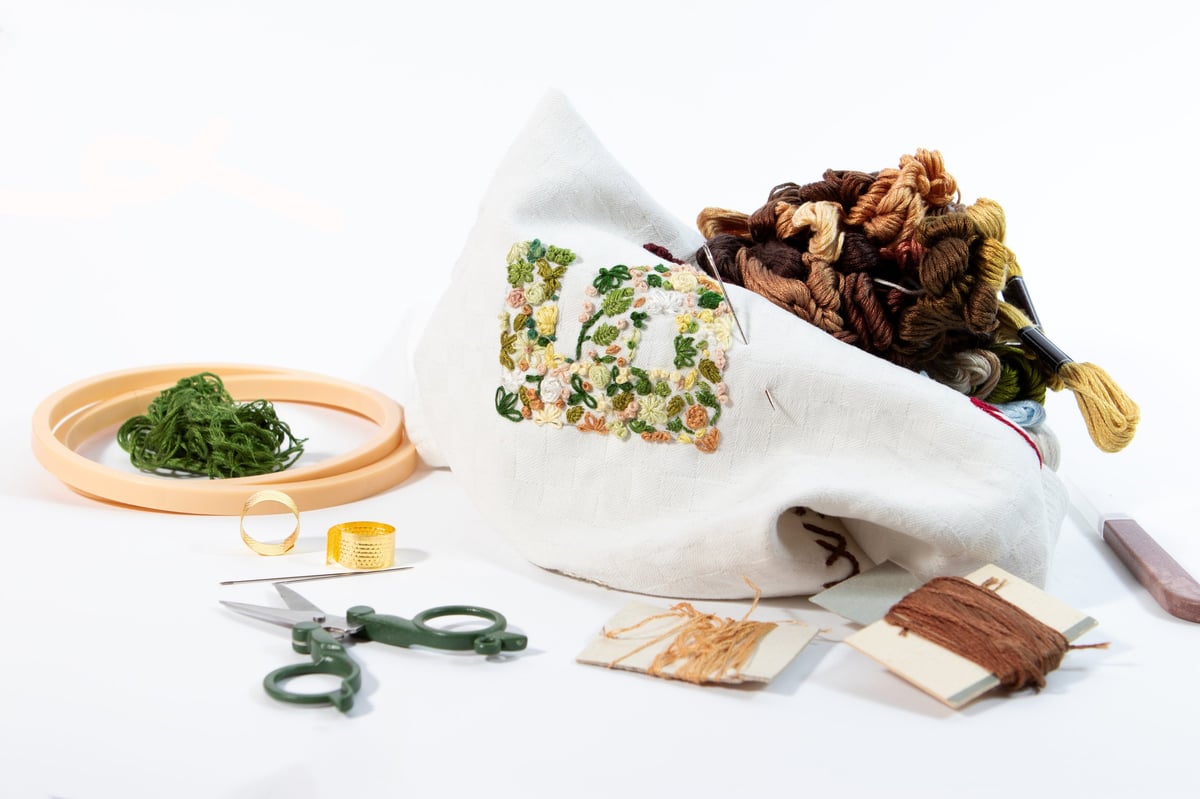 Colección de flores bordadas a mano rodeadas de materiales y herramientas de bordado