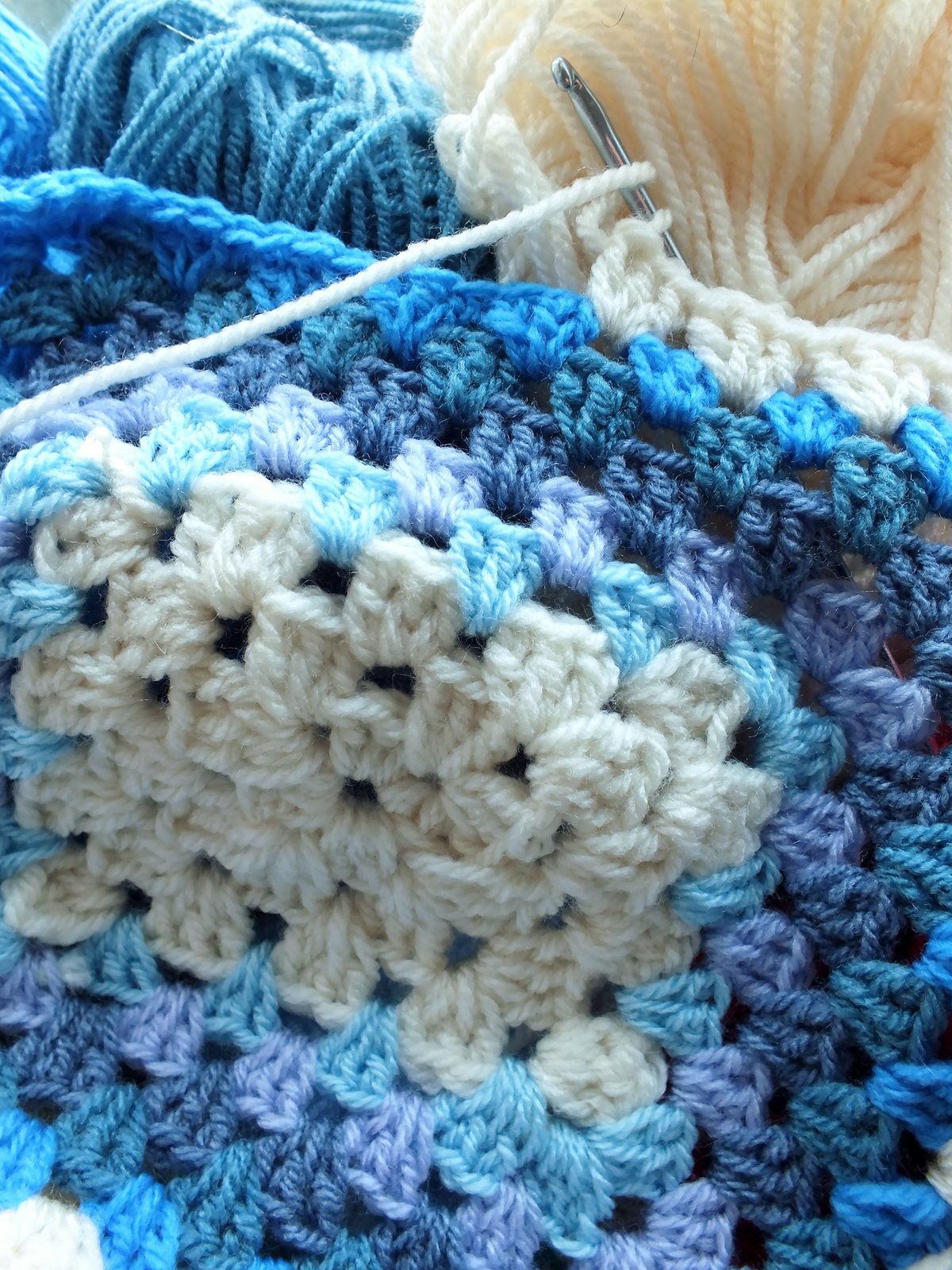 Granny square azul y crema tejido a crochet con ovillo y aguja