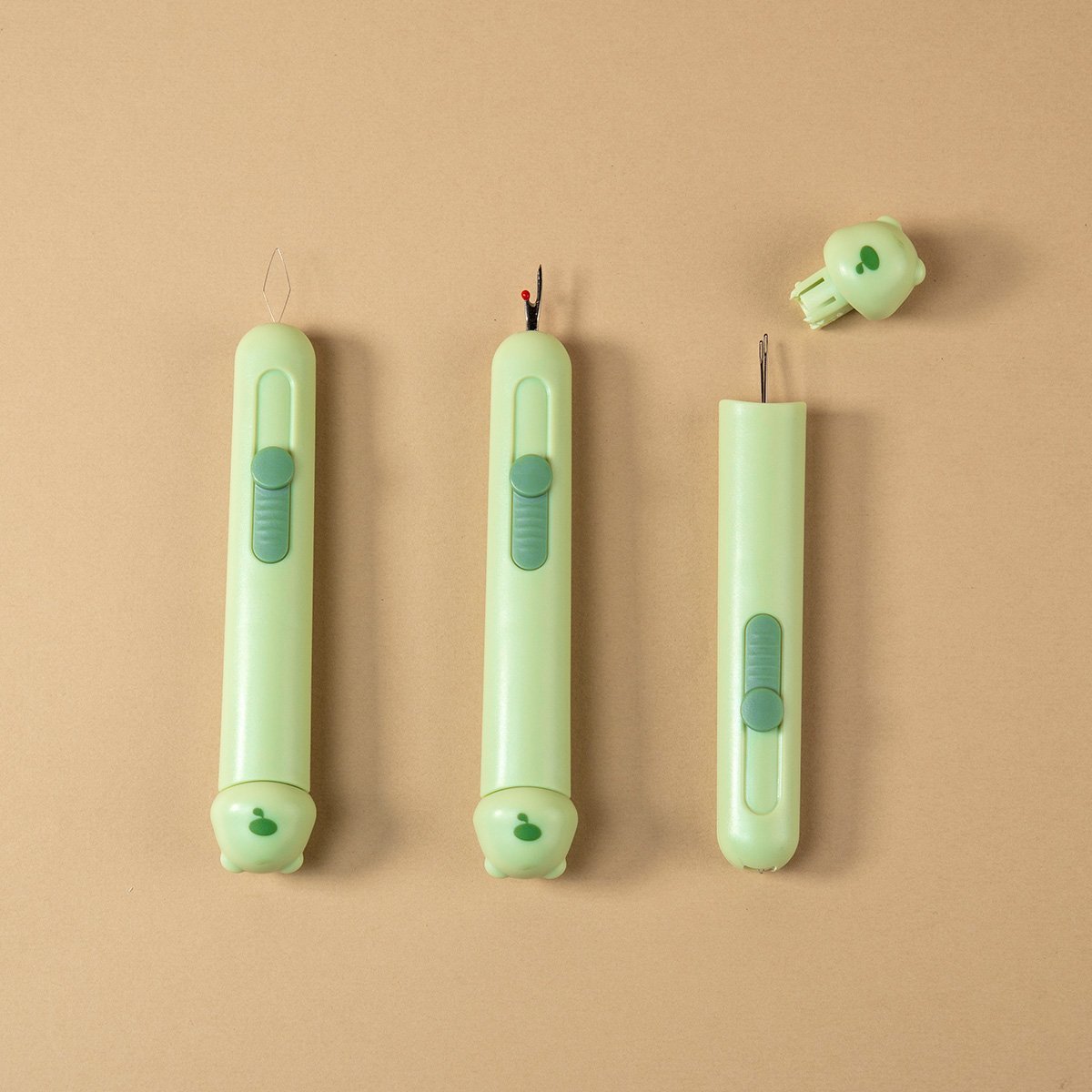 Set de tres herramientas verdes menta para punch needle con punta metálica, mango ergonómico y tapa removible, dispuestas sobre fondo beige