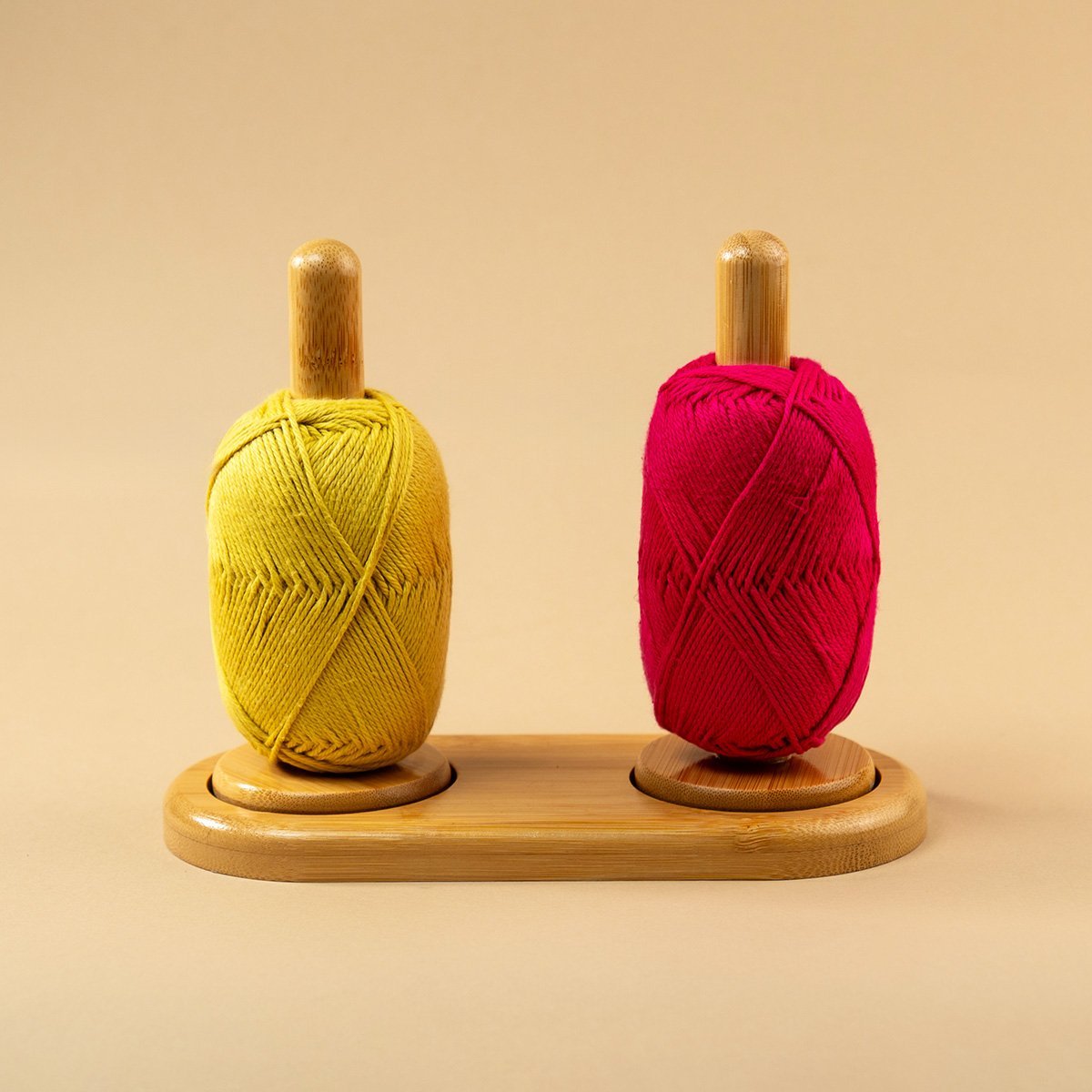 Soporte doble de madera con un ovillo de lana amarillo y otro rojo, listos para tejer